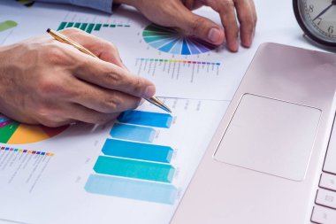 Veri grafikleri ile dizüstü bilgisayar üzerinde çalışan iş adamı elinde