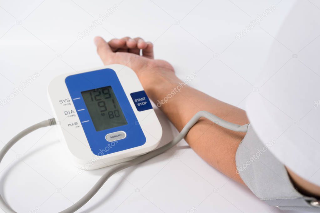 Digital Blood Pressure Monitor with the arm of a man on white background