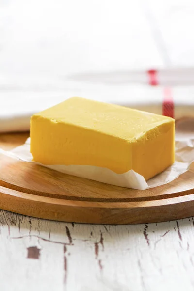 Bloque de mantequilla sobre tabla de madera — Foto de Stock