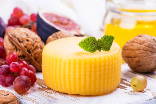 Rueda de queso amarillo con especias y snacks — Foto de Stock