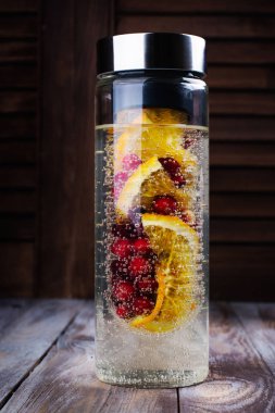 Kızılcık ve turuncu renkte bir cam şişe ile su infüzyon