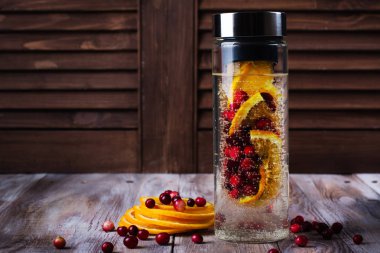 Kızılcık ve turuncu renkte bir cam şişe ile su infüzyon