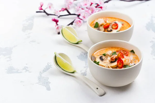 Traditionelle Tom-Yum-Suppe mit blühendem Sakura-Zweig auf weißem Stein-Tisch — Stockfoto