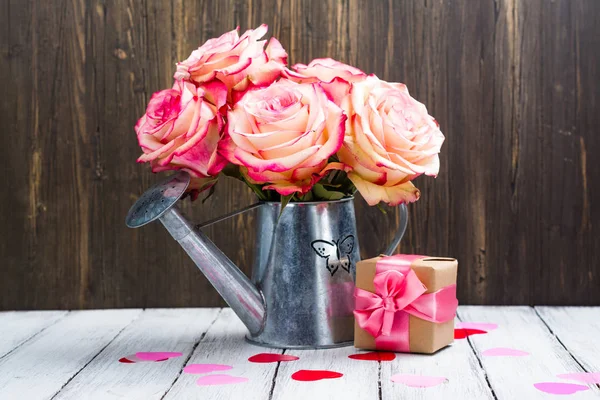 Hermosa rosa rosa en una lata de riego sobre fondo de madera — Foto de Stock