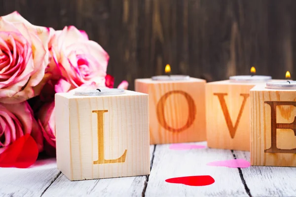 День Святого Валентина: горящие свечи и слово Любовь из деревянных подсвечников — стоковое фото