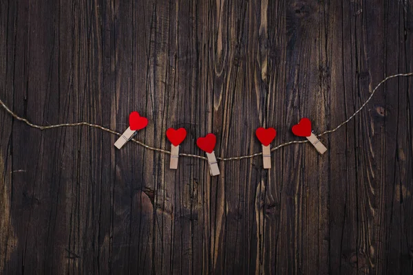 Pequeño tendedero de madera con corazones rojos colgando de una cuerda — Foto de Stock