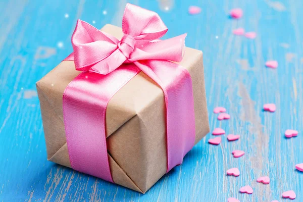 Gift box with pink bow ribbon and glitter hearts on blue spring background — Stock Photo, Image