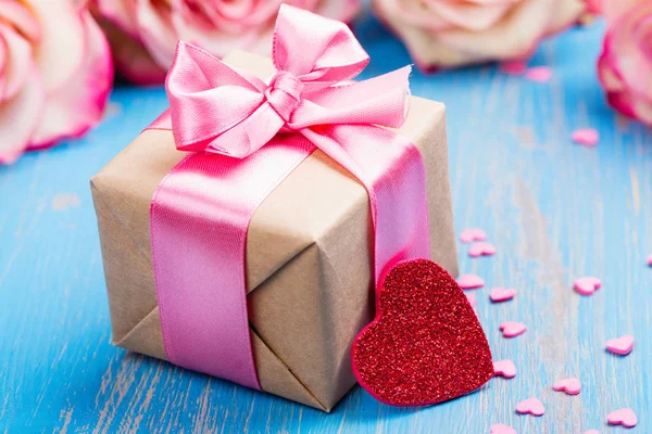 Geschenkdoos met roze boog lint en glitter hart op blauwe lente achtergrond — Stockfoto