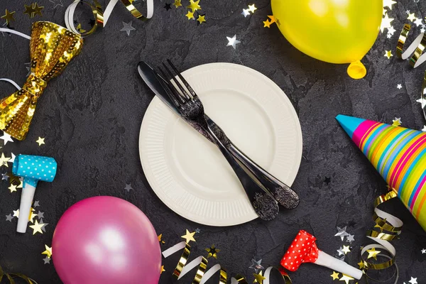 Prostřený stůl světlé slavnostní karneval s talíř a příbory na černý kamenný stůl zdobený párty Doplňky — Stock fotografie