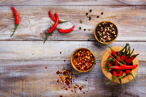 Rote Chilischoten im Holzmörser, Pfefferflocken und Pfefferkörner in Holzschalen — Stockfoto