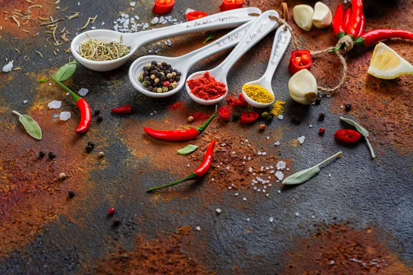 Dry herbs and spices in measuring spoons on white stone kitchen table — Stock Photo, Image