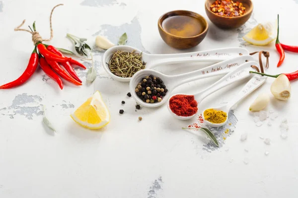 Suche zioła i przyprawy w łyżki miarowe na stół biały kamień kuchnia — Zdjęcie stockowe