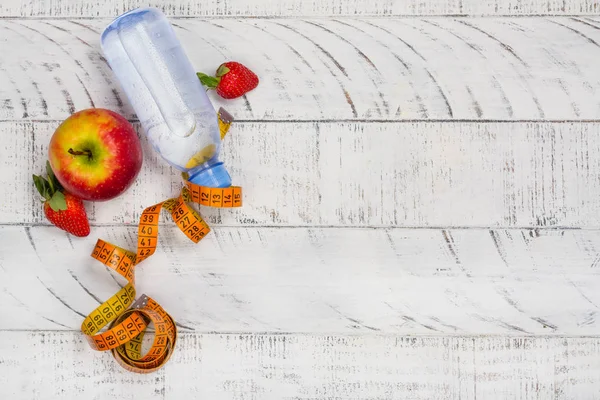 Яблоко, бутылка воды и измерительная лента на белом фоне — стоковое фото
