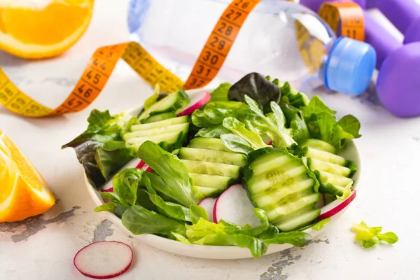 Salada vegetariana saudável, halteres e garrafa de água na mesa de madeira — Fotografia de Stock