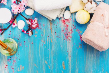 Pamuk havlu, aroma yağı, deniz tuzu ve taşlar mavi zemin üzerine Spa kompozisyonu