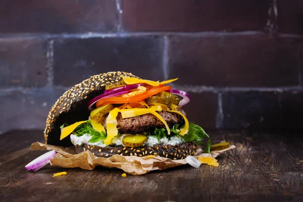 Hambúrguer preto caseiro com molho tzatziki, queijo desfiado e massa de carne — Fotografia de Stock