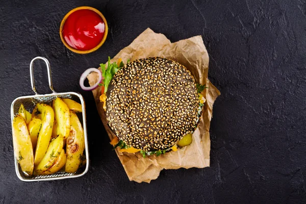 Hamburger nero fatto in casa con salsa tzatziki, formaggio triturato e stucco di carne. Cunei di patate arrosto e ketchup . — Foto Stock