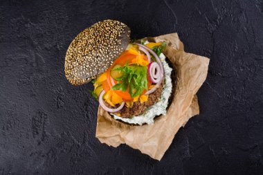 Ev yapımı siyah burger tzatziki sos, rendelenmiş peynir ve et macun