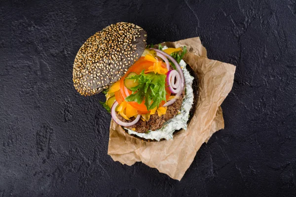 Hambúrguer preto caseiro com molho tzatziki, queijo desfiado e massa de carne — Fotografia de Stock