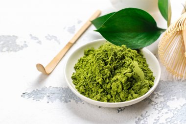 Beyaz zemin üzerine yeşil matcha çay toz ve çay aksesuarları
