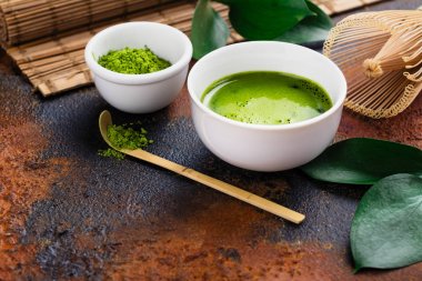 Karanlık paslı zemin üzerine yeşil matcha çay içecek ve çay aksesuarları