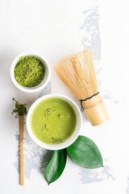 Beyaz zemin üzerine yeşil matcha çay içecek ve çay aksesuarları