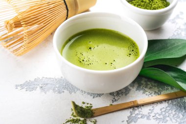 Beyaz zemin üzerine yeşil matcha çay içecek ve çay aksesuarları