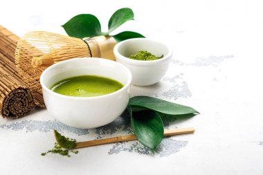 Beyaz zemin üzerine yeşil matcha çay içecek ve çay aksesuarları
