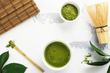 Beyaz zemin üzerine yeşil matcha çay içecek ve çay aksesuarları
