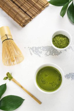 Beyaz zemin üzerine yeşil matcha çay içecek ve çay aksesuarları
