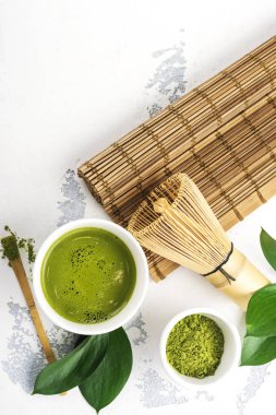 Beyaz zemin üzerine yeşil matcha çay içecek ve çay aksesuarları