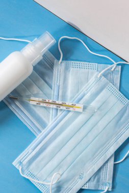 Koronavirüsün önlenmesi için dezenfekte spreyi veya antibakteriyel sabun ve yüz maskesi, üst görünüm, sıcaklık ve arka plan termometresi