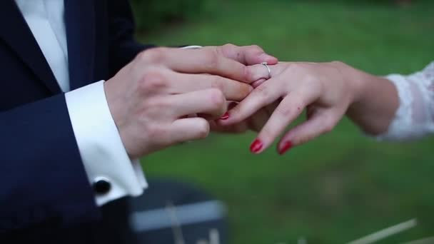 Жених кладет кольцо на руку невесты — стоковое видео