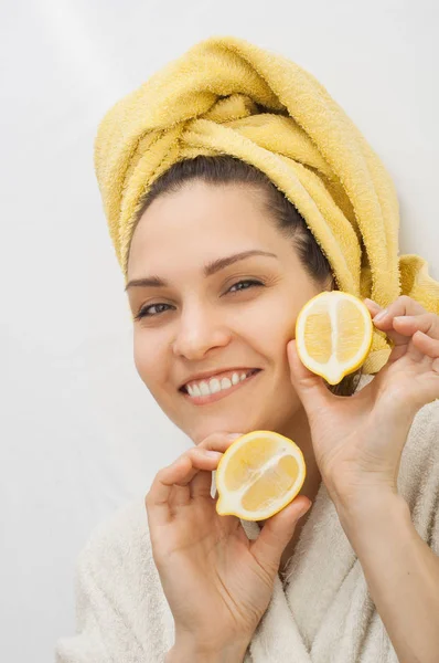 Seorang gadis dengan handuk di kepalanya memegang dua bagian dari lemon — Stok Foto