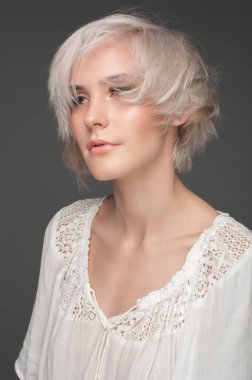 Beyaz bluz içinde sakin sarışın. Koyu gri bir arkaplanda