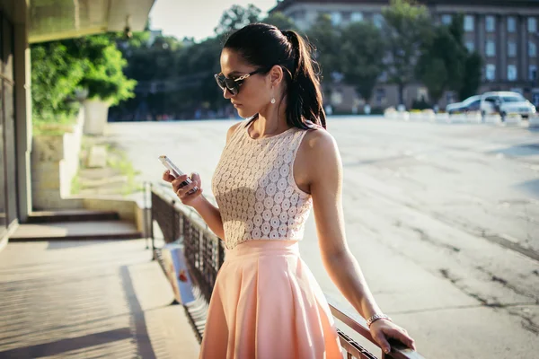 Jonge vrouw verblijft met telefoon na het winkelen — Stockfoto