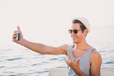 Gülümseyen genç hipster adam ve yapmak telefon selfie