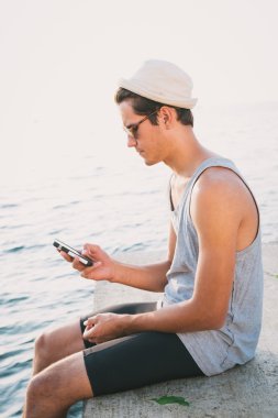 Genç hipster adam akıllı telefon denize yakın kullanarak onun sabit vites bisiklet ile