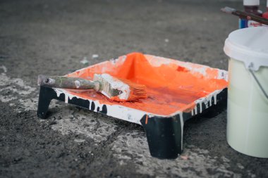 Turuncu renk boya ve fırça asfalt üzerinde