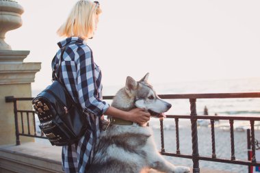 Genç kadın, gündoğumu, deniz cephesinde Sibirya husky köpek
