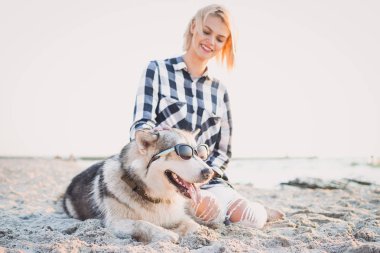 Genç erkek Sibirya husky köpek ile kumsalda güneş doğarken oynuyor.