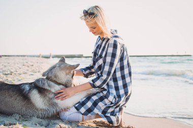 Genç erkek ile Sibirya husky köpek sahilde güneş doğarken sarılma