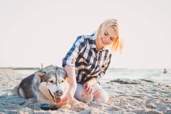 Jovem fêmea colocando óculos de sol no cão husky siberiano na praia — Fotografia de Stock