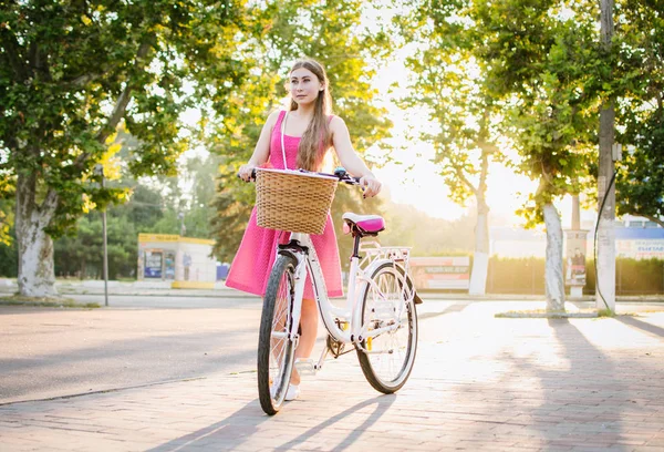 Jovem mulher com bicicleta da cidade indo no parque ao nascer do sol ou pôr do sol — Fotografia de Stock