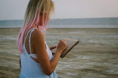 Kalem sahilinde ile çizim pembe saçlı genç hipster kadın