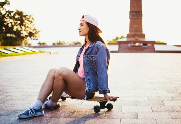 해돋이 또는 일몰에 공원에서 longboard에 앉아 어린 소녀 — 스톡 사진