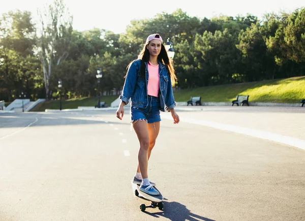 Menina montando longboard no parque ao nascer do sol ou pôr do sol — Fotografia de Stock