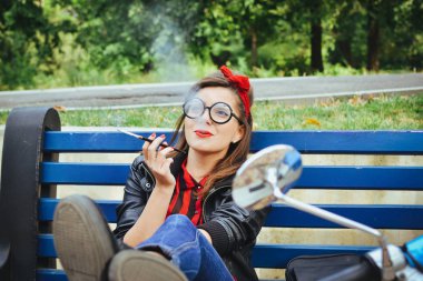 Bir tezgah ve Sigara İçilmeyen üzerinde oturan gözlüklü genç hipster kadın