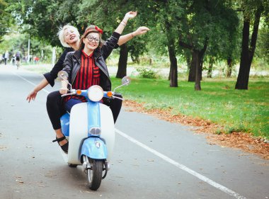 İki genç kadın parkta vintage scooter ile biraz eğlenmek