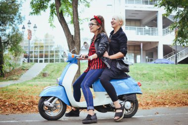 İki genç kadın parkta vintage scooter ile biraz eğlenmek